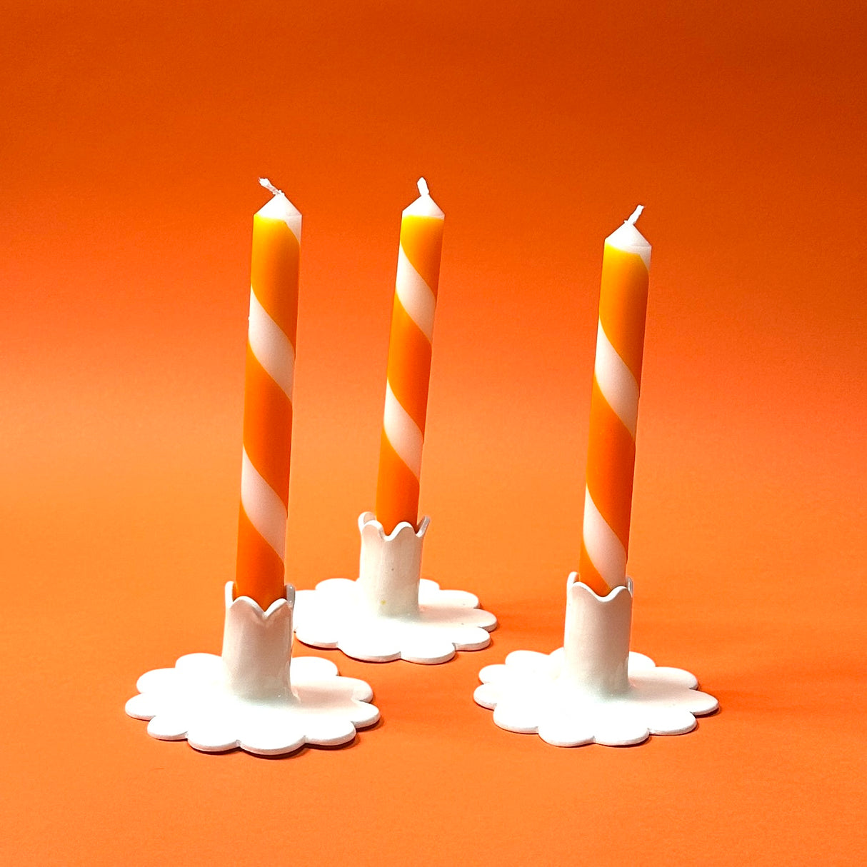 Three orange and white stripe halloween taper candles, on a white background.