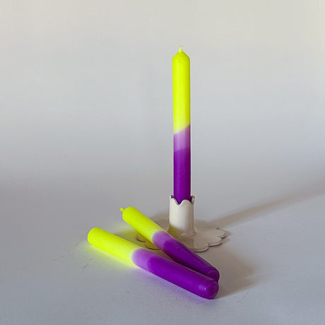 Three taper candles with a purple top and green bottom, displayed on a white surface.