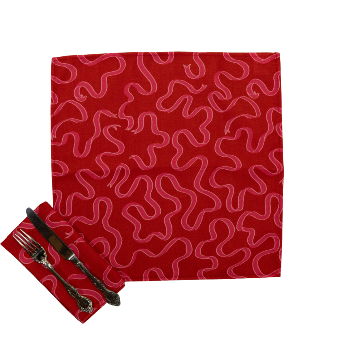 a dark red cloth dinner napkin printed with pink ribbon motifs