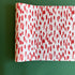 A white and red paper table runner featuring a brushtroke pattern called Club House by Madcap Cottage