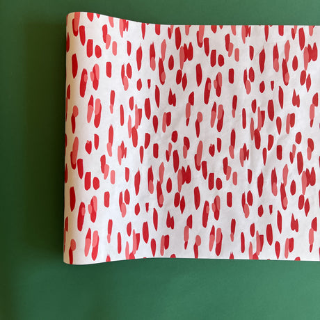A white and red paper table runner featuring a brushtroke pattern called Club House by Madcap Cottage