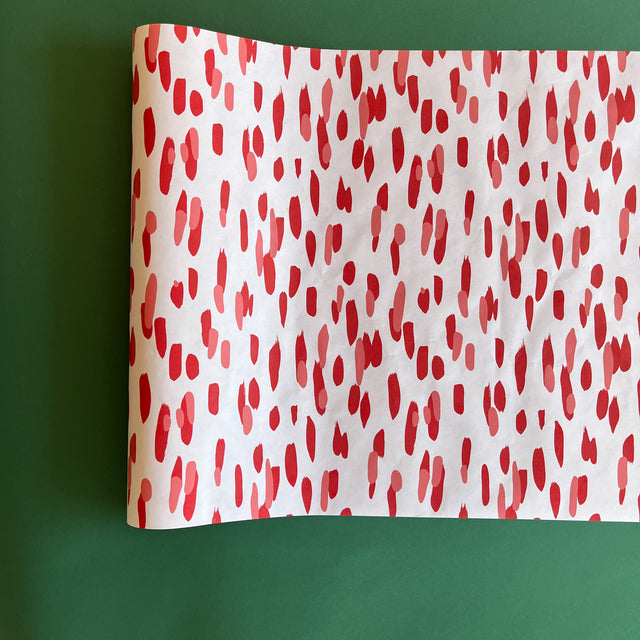 A white and red paper table runner featuring a brushtroke pattern called Club House by Madcap Cottage