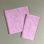 Hampton Court two shell pink cloth dinner napkins on a green background.