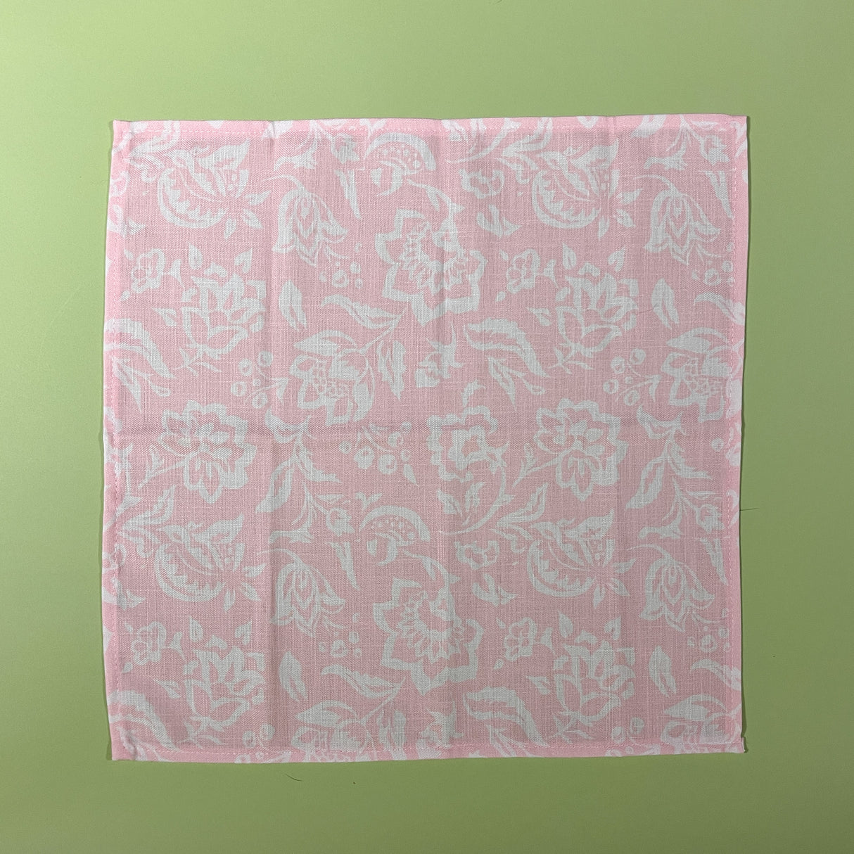 Flat view of Hampton Court shell pink cloth dinner napkin with a white floral motif.
