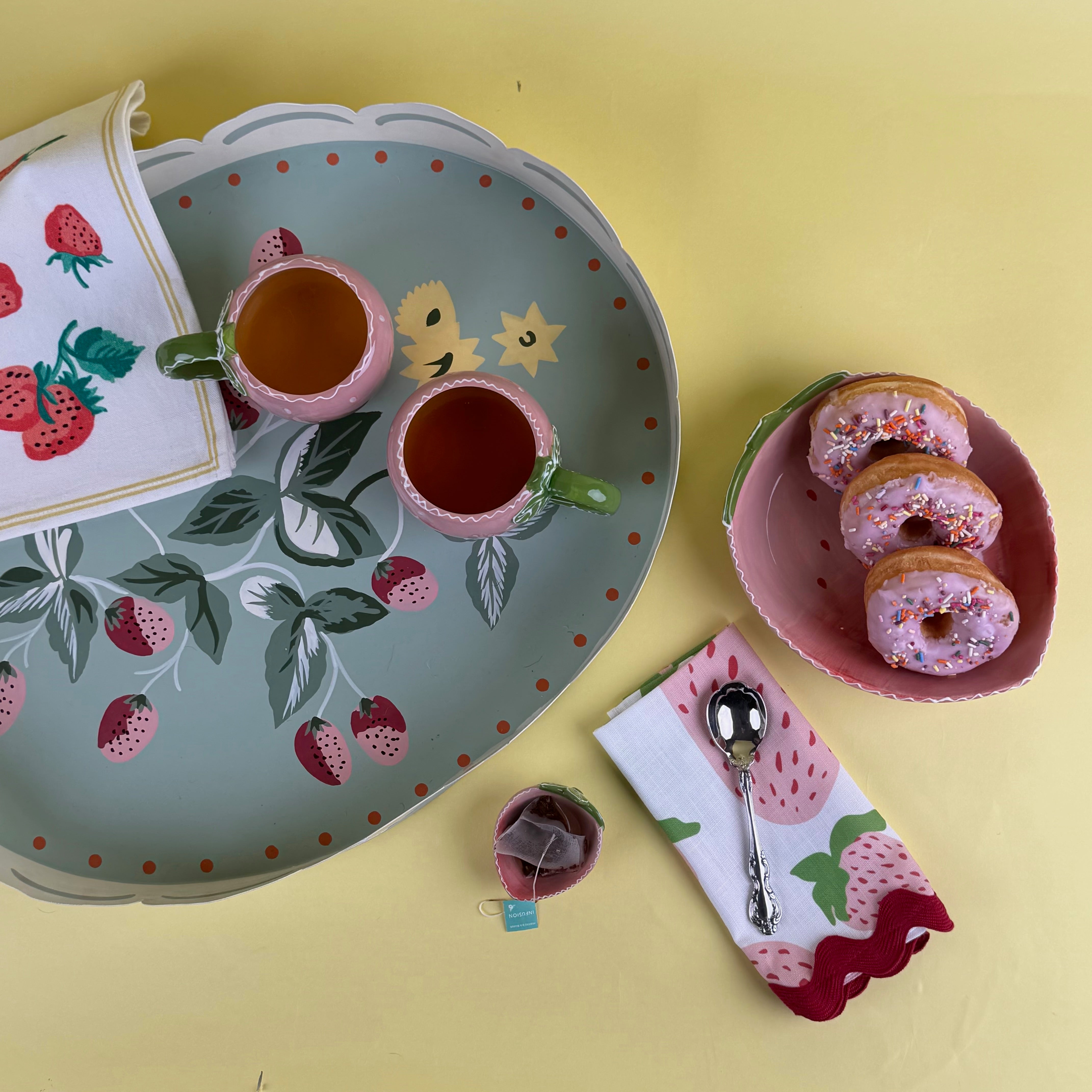 strawberry kitchen decor spring collection with tray, mugs, napkin, and strawberry themed table setting.
