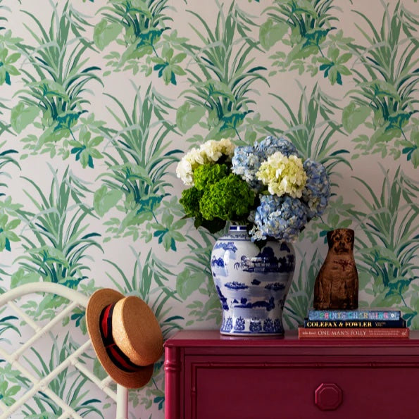 Botanical wallpaper backdrop styled with a blue and white ceramic vase, hydrangea arrangement, books, and decorative objects.