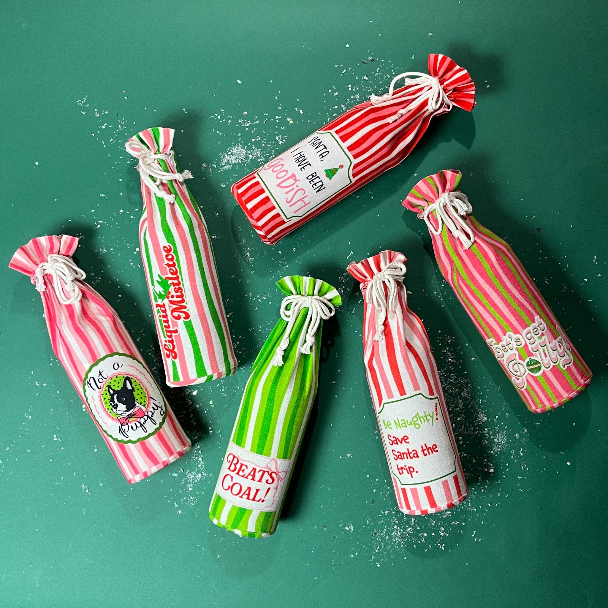 Holiday wine bottle gift bags in pink, red, and green stripes with humorous Christmas sayings, perfect for gifting and entertaining.