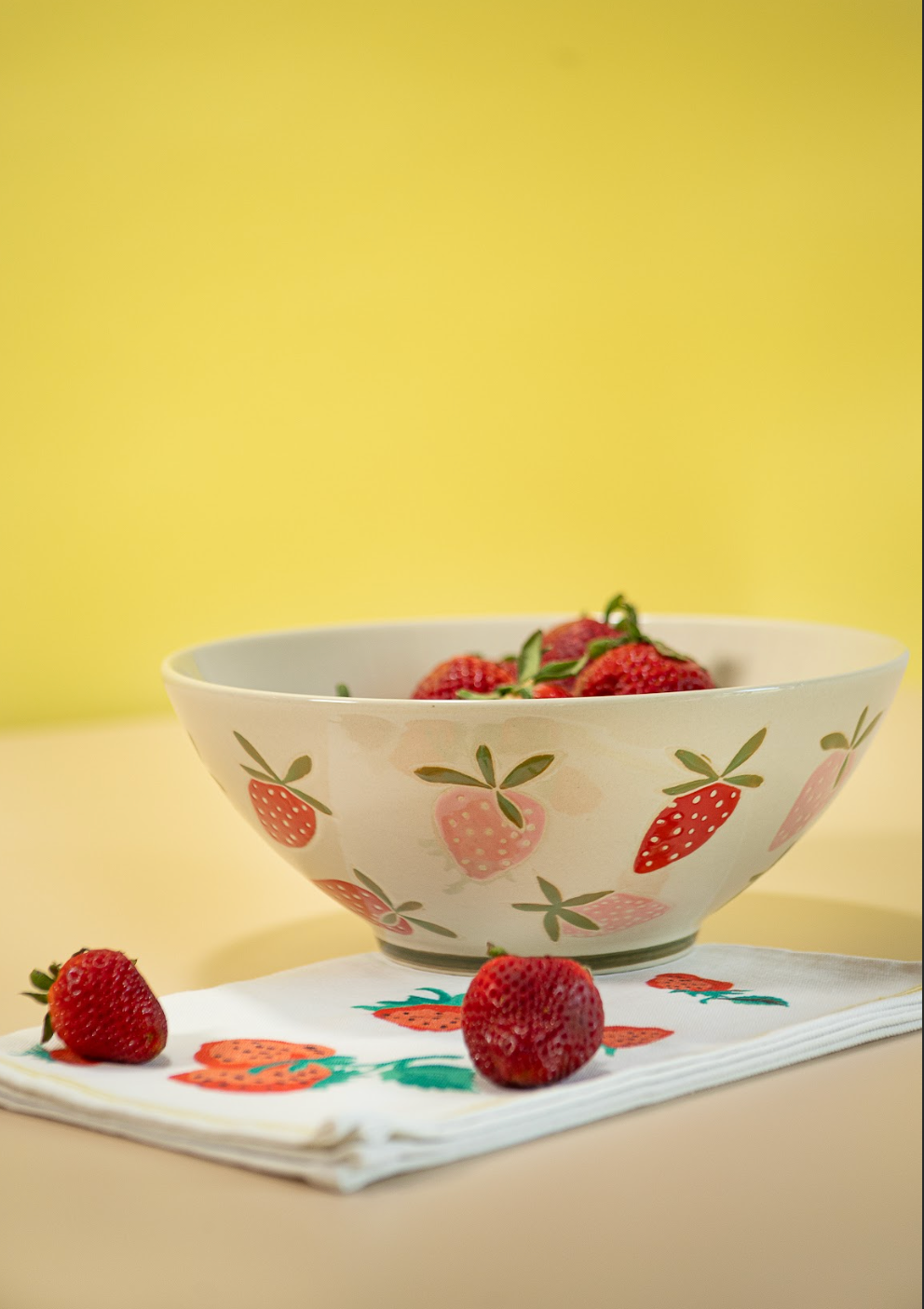 A large strawberry serving bowl with white and pink strawberry motifs decorating the exterior