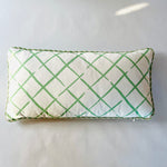 a green and white throw pillow with a criss cross motif and green piping.