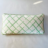 a green and white throw pillow with a criss cross motif and green piping.