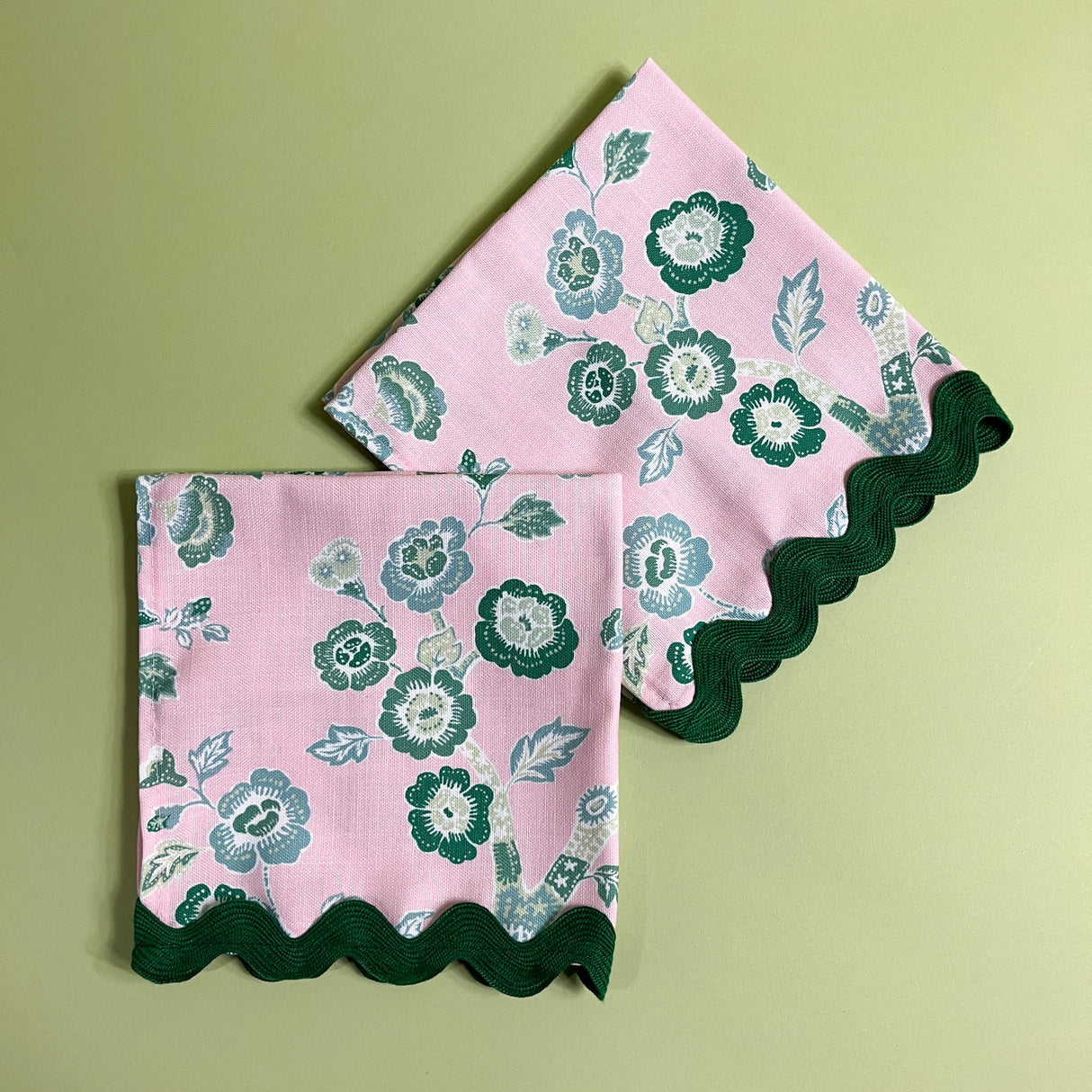 pink and green chinoiserie napkins in temple garden print madcap cottage fabric on a light green background. 