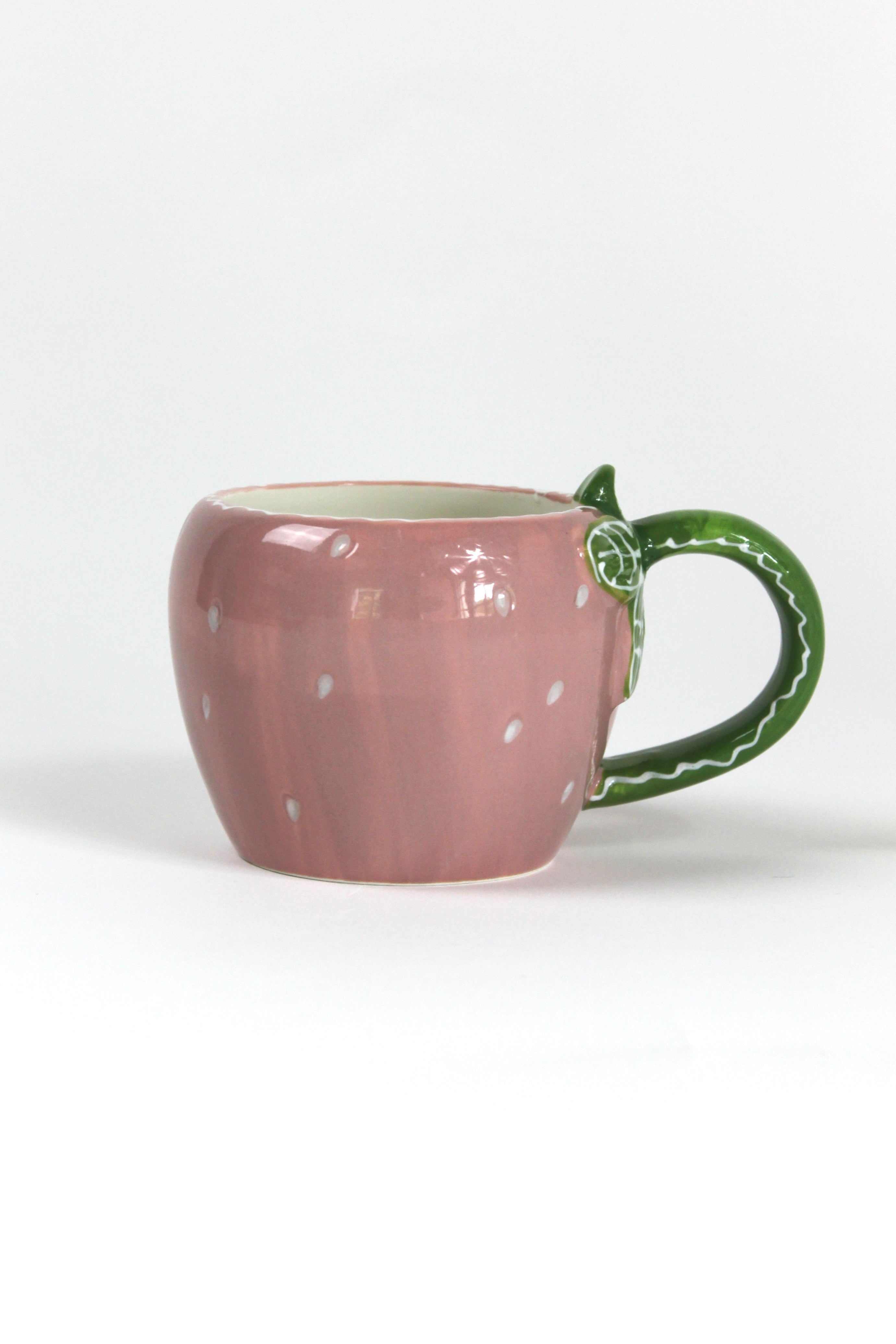 a pink ceramic strawberry mug with a green leafy handle