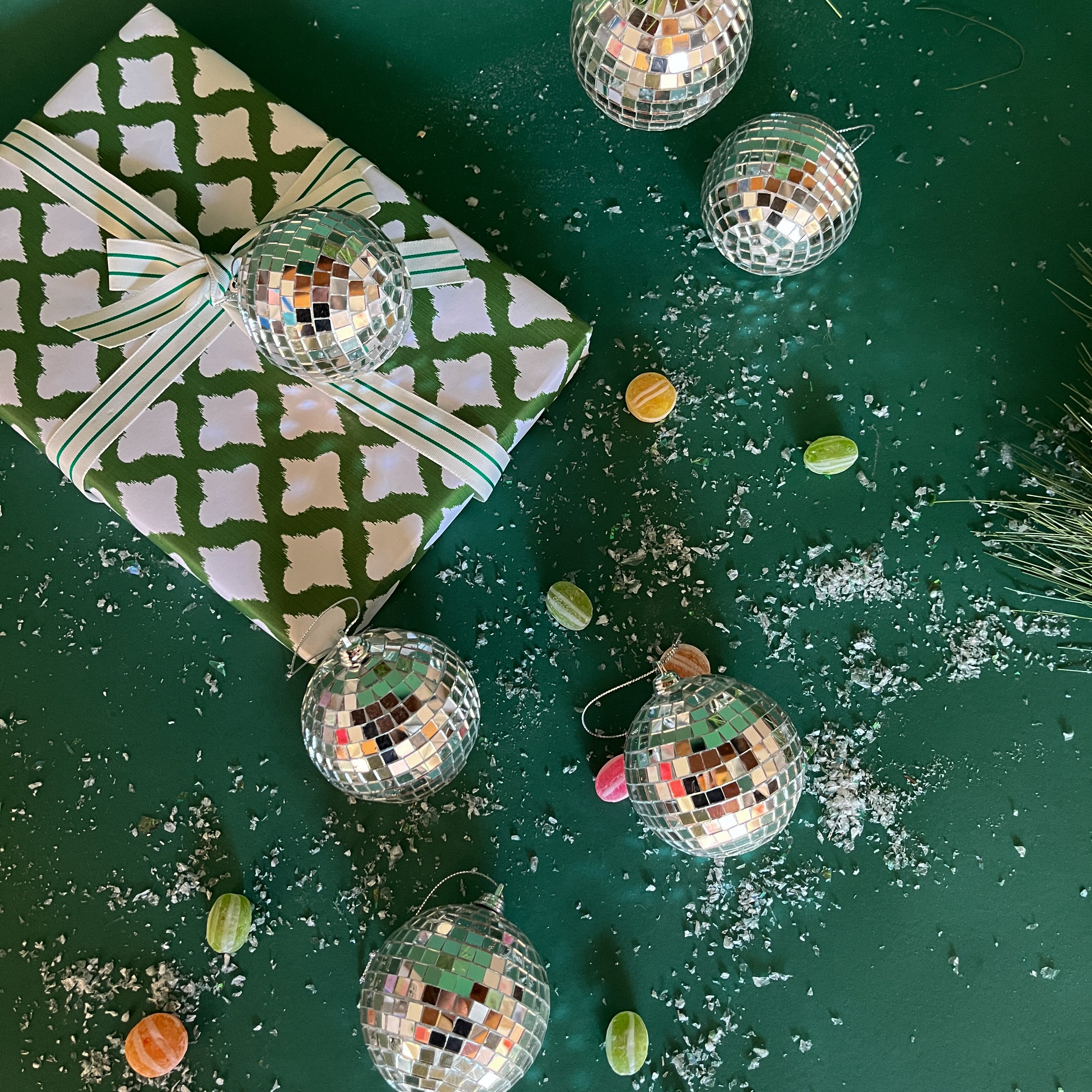 six silver disco ball christmas ornaments on a snow covered green background