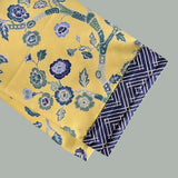 a folded yellow chinoiserie tea towel with blue cherry blossom motifs.