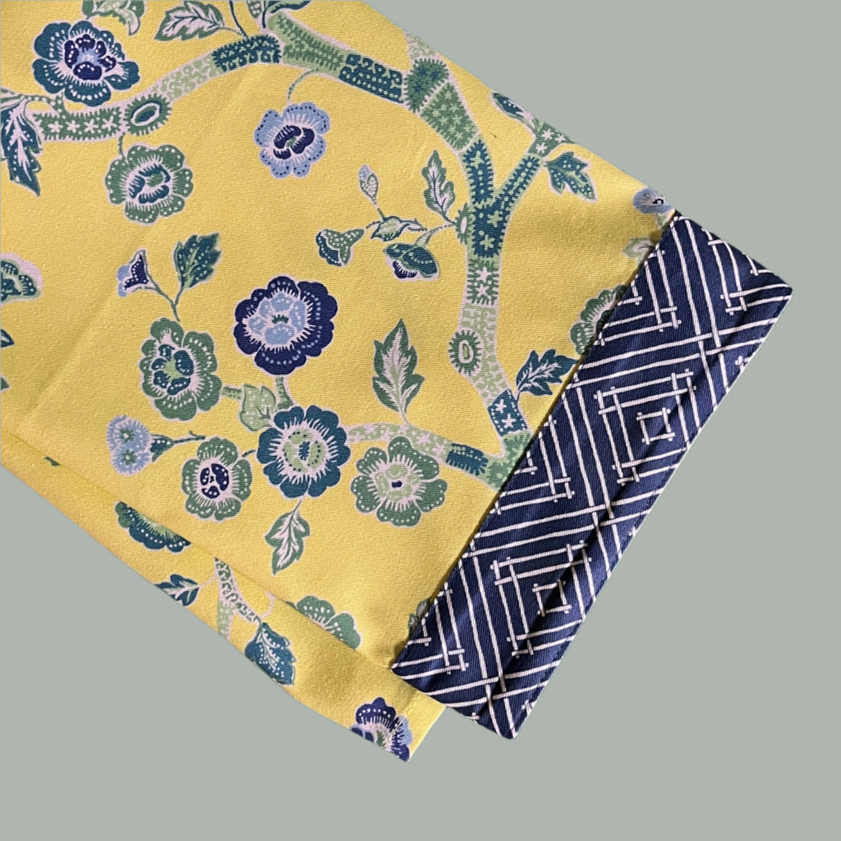 a folded yellow chinoiserie tea towel with blue cherry blossom motifs. 