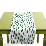 Green and white table runner with abstract green brushstroke dots displayed on a light green table.