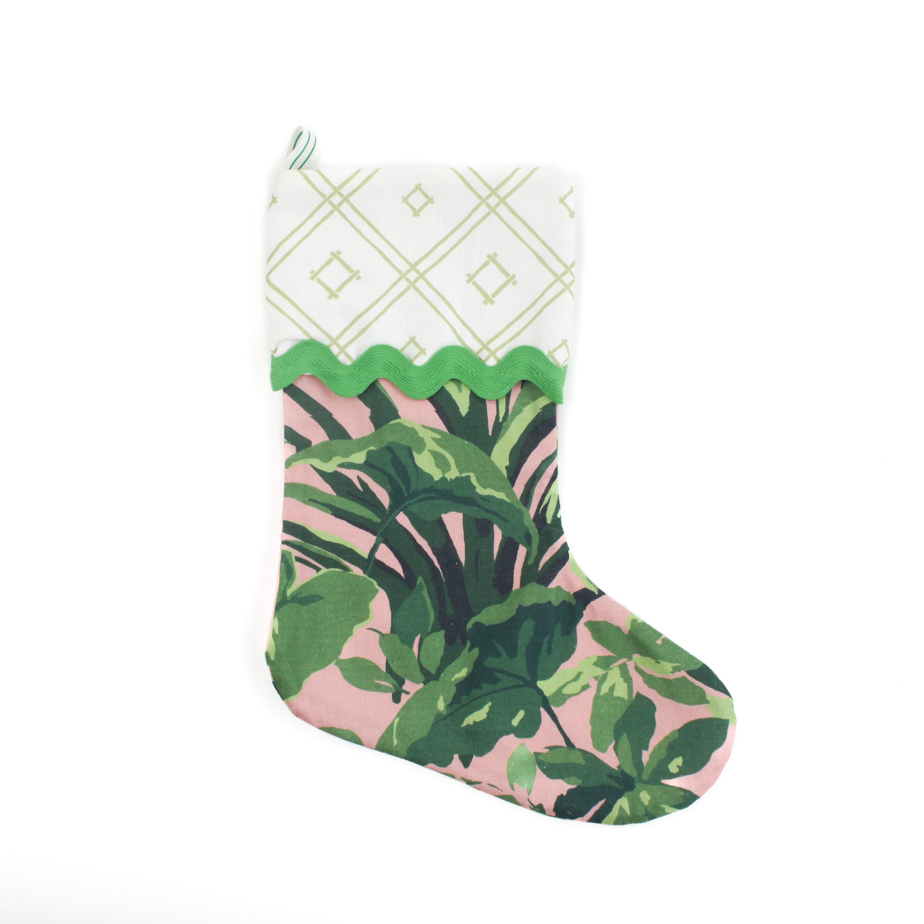 A palm leaf print pink and green Christmas stocking on a white background