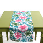 Colorful snowflake table runner displayed on a green table.
