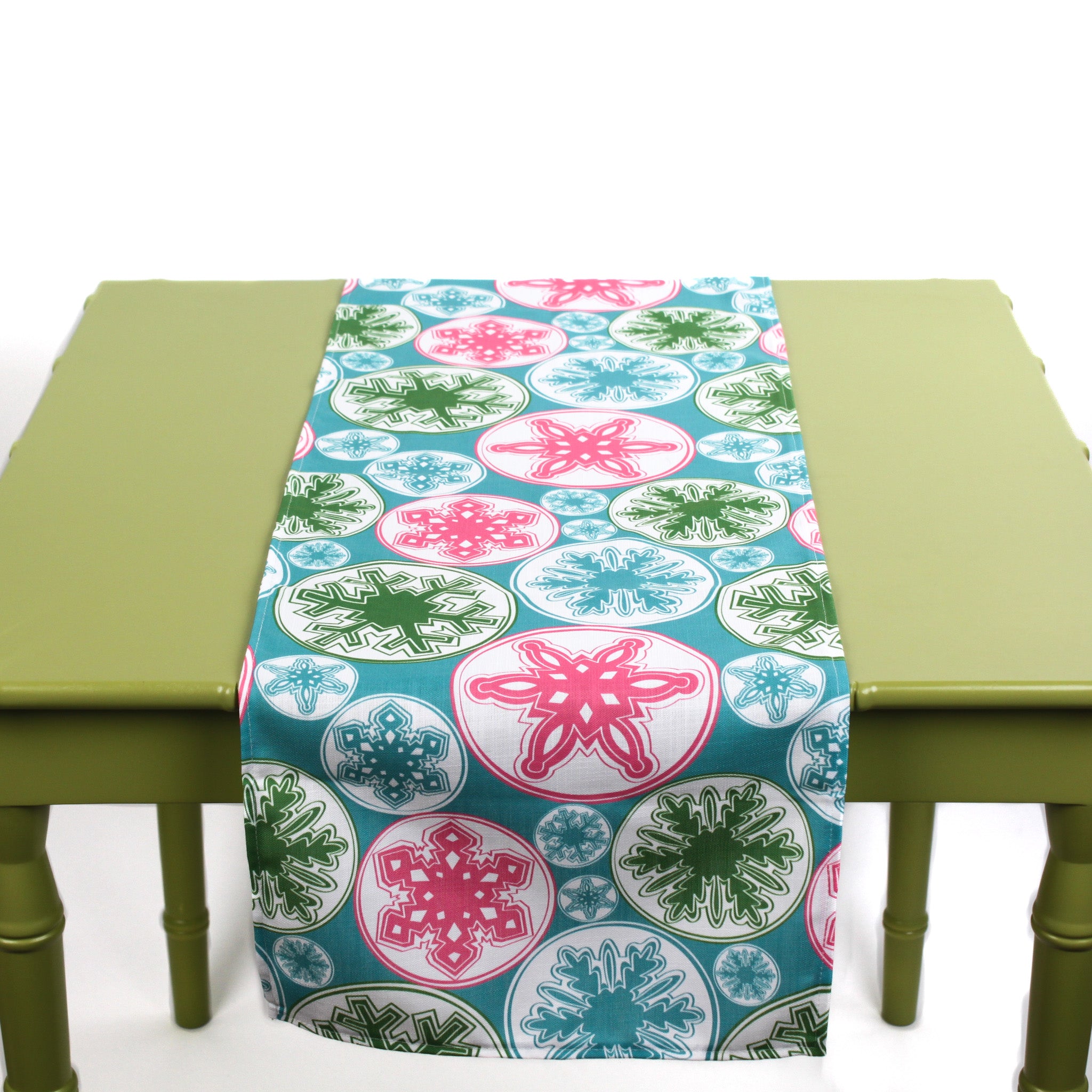Colorful snowflake table runner displayed on a green table.