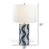 A blue and white table lamp featuring a white porcelain base with blue squiggle motif and a white lampshade with arrows denoting the lamp dimensions 31" high by 18" across 
