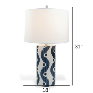 A blue and white table lamp featuring a white porcelain base with blue squiggle motif and a white lampshade with arrows denoting the lamp dimensions 31" high by 18" across 