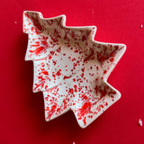 a christmas tree shaped red and white vintage plate against a red background. 