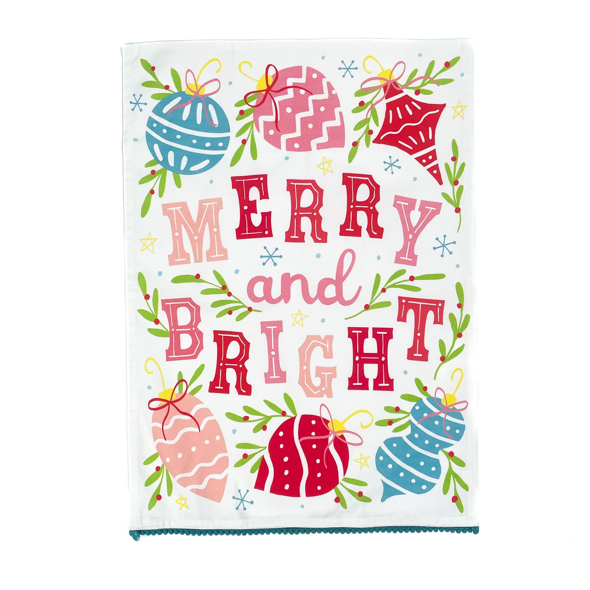 colorful christmas tea towel with with ornament motifs, blue pom pom trim and text that reads "Merry and Bright" against a white background. 