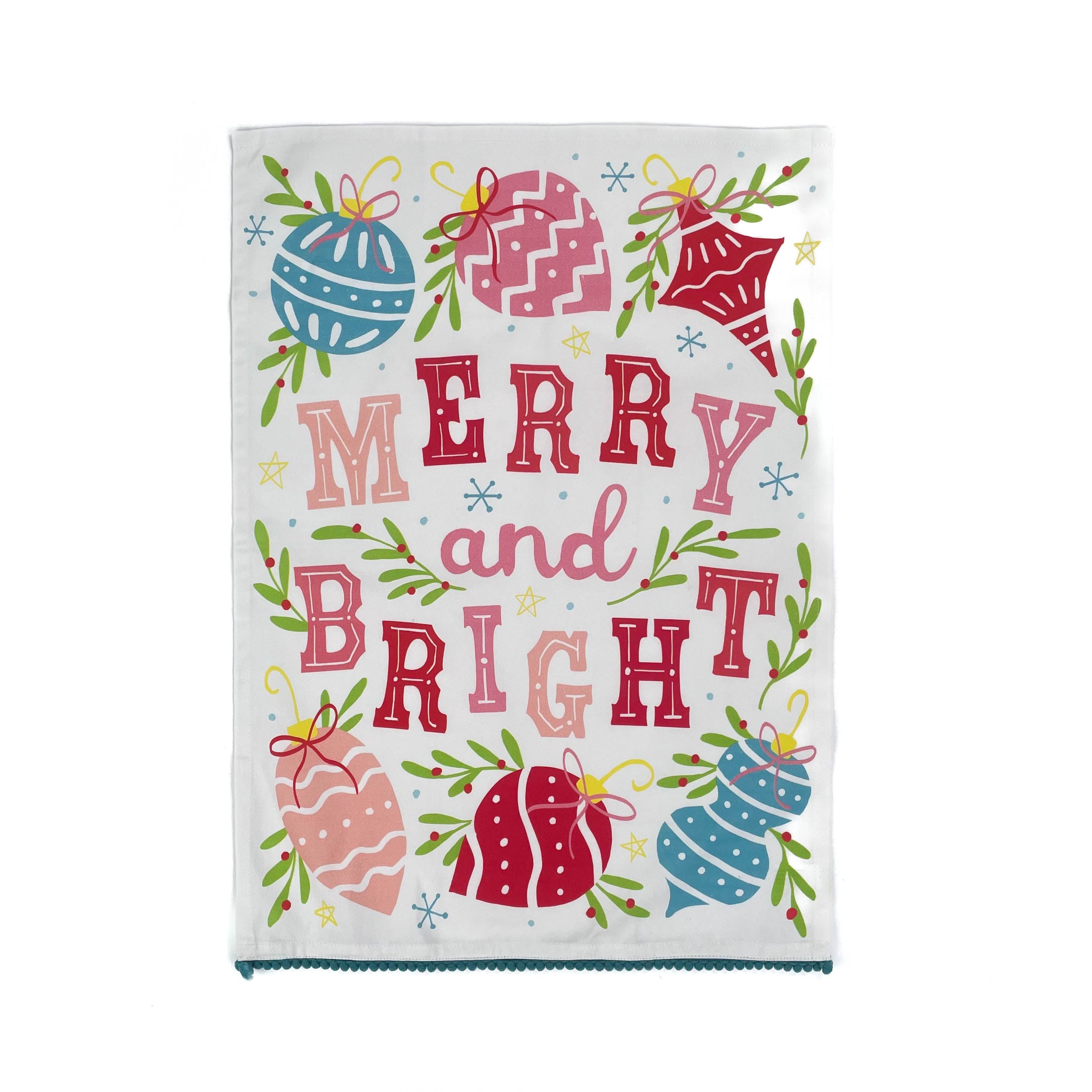 colorful christmas tea towel with with ornament motifs, blue pom pom trim and text that reads "Merry and Bright" against a white background. 