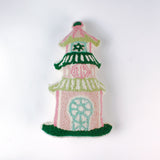 Decorative pillow shaped like a pagoda, featuring a pink base with green and white tiered roofs and intricate embroidered details in soft pastel colors.