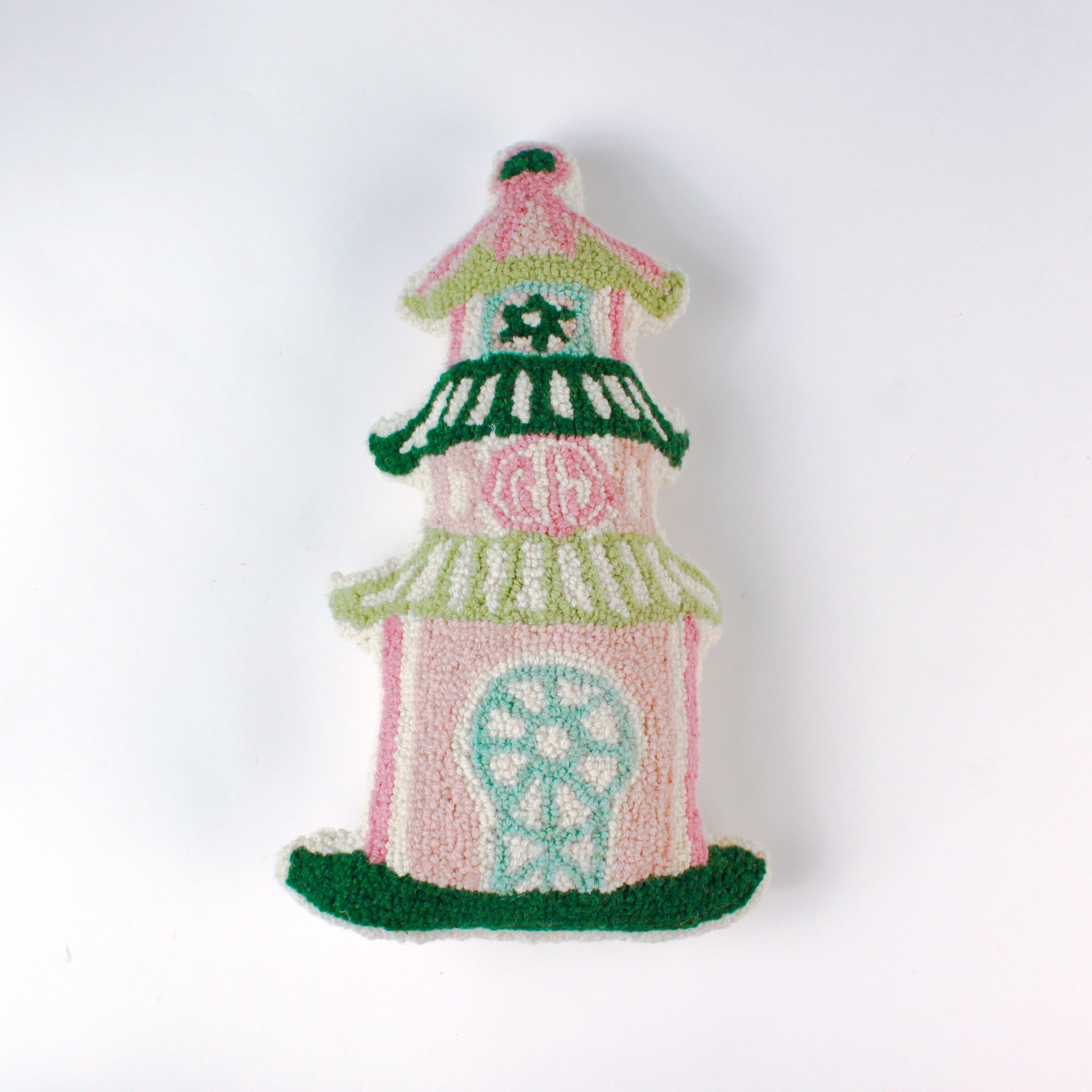 Decorative pillow shaped like a pagoda, featuring a pink base with green and white tiered roofs and intricate embroidered details in soft pastel colors.