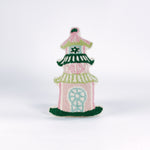 Decorative pillow shaped like a pagoda, featuring a pink base with green and white tiered roofs and intricate embroidered details in soft pastel colors.