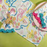 a multicolored bunnies and bow print cloth table runner and napkins on a plate
