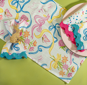 a multicolored bunnies and bow print cloth table runner and napkins on a plate