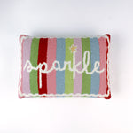 Rectangular colorful pillow with vertical stripes in red, pink, green, blue, and lavender, featuring the word “sparkle” written in white cursive with a small gold star above the letter “k.”