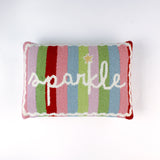 Rectangular colorful pillow with vertical stripes in red, pink, green, blue, and lavender, featuring the word “sparkle” written in white cursive with a small gold star above the letter “k.”