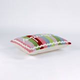 side of a Rectangular pillow with colorful vertical stripes in red, pink, green, blue, and lavender, featuring the word “sparkle” written in white cursive with a small gold star above the letter “k.”