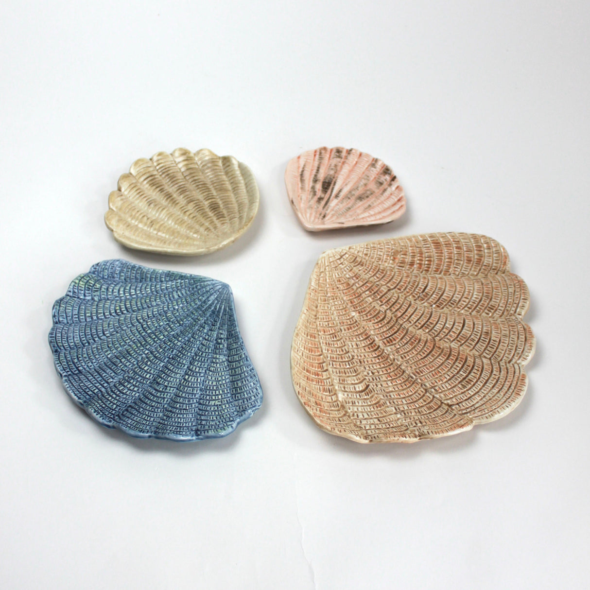 A collection of 4 nested ceramic shell bowls in graduating sizes. 