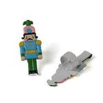 two metal blue, pink and green nutcracker shaped christmas napkin rings on a white background. 