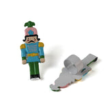 two metal blue, pink and green nutcracker shaped christmas napkin rings on a white background. 