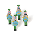 four metal blue, pink and green nutcracker shaped christmas napkin rings on a white background. 