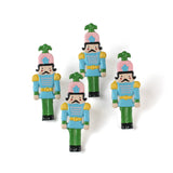 four metal blue, pink and green nutcracker shaped christmas napkin rings on a white background. 