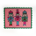 PInk and green christmas rug featuring three nutcrackers and a green scalloped border