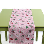 Pink Christmas-themed table runner with playful holiday icons displayed on a green table.