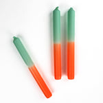 3 orange and green taper candles lying in a white background