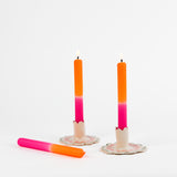 pink and orange taper candles in white scalloped candle holders