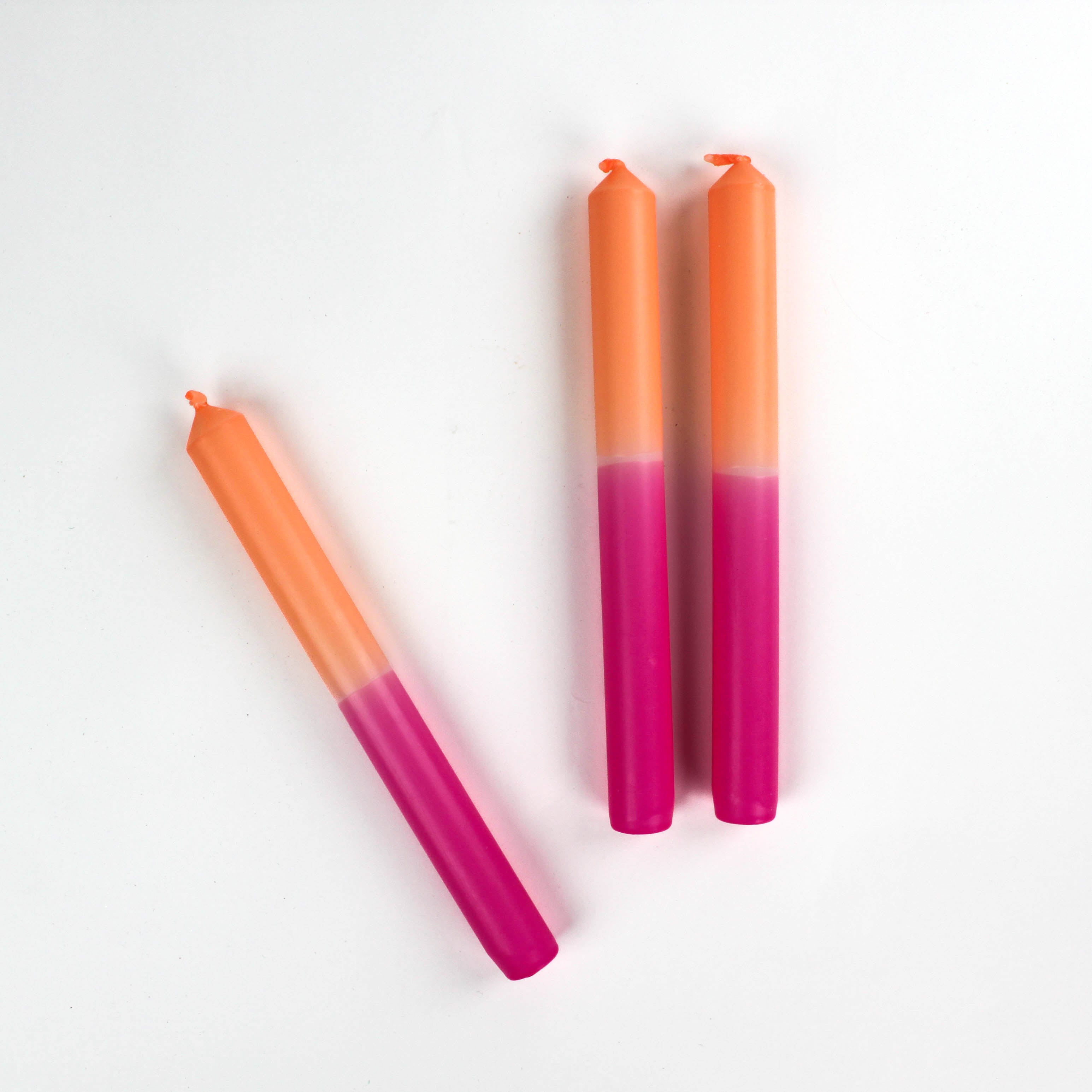 three pink and orange taper candles