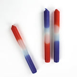 a trio of colorful taper candles in a mix of white, blue and orange. 