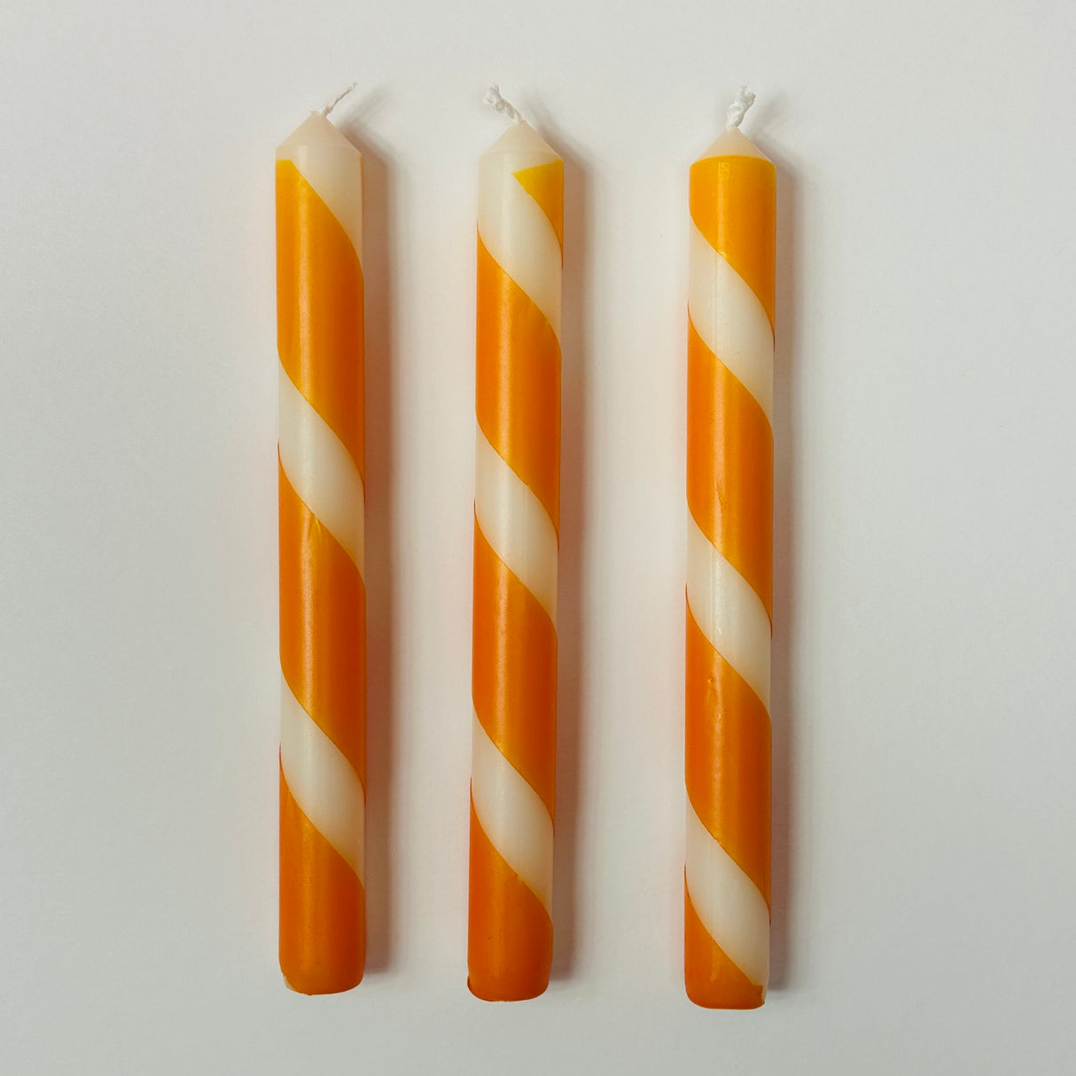 Three orange and white stripe taper candles.