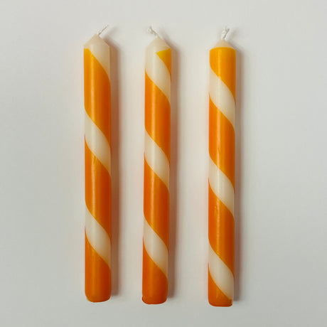 Three orange and white stripe taper candles.