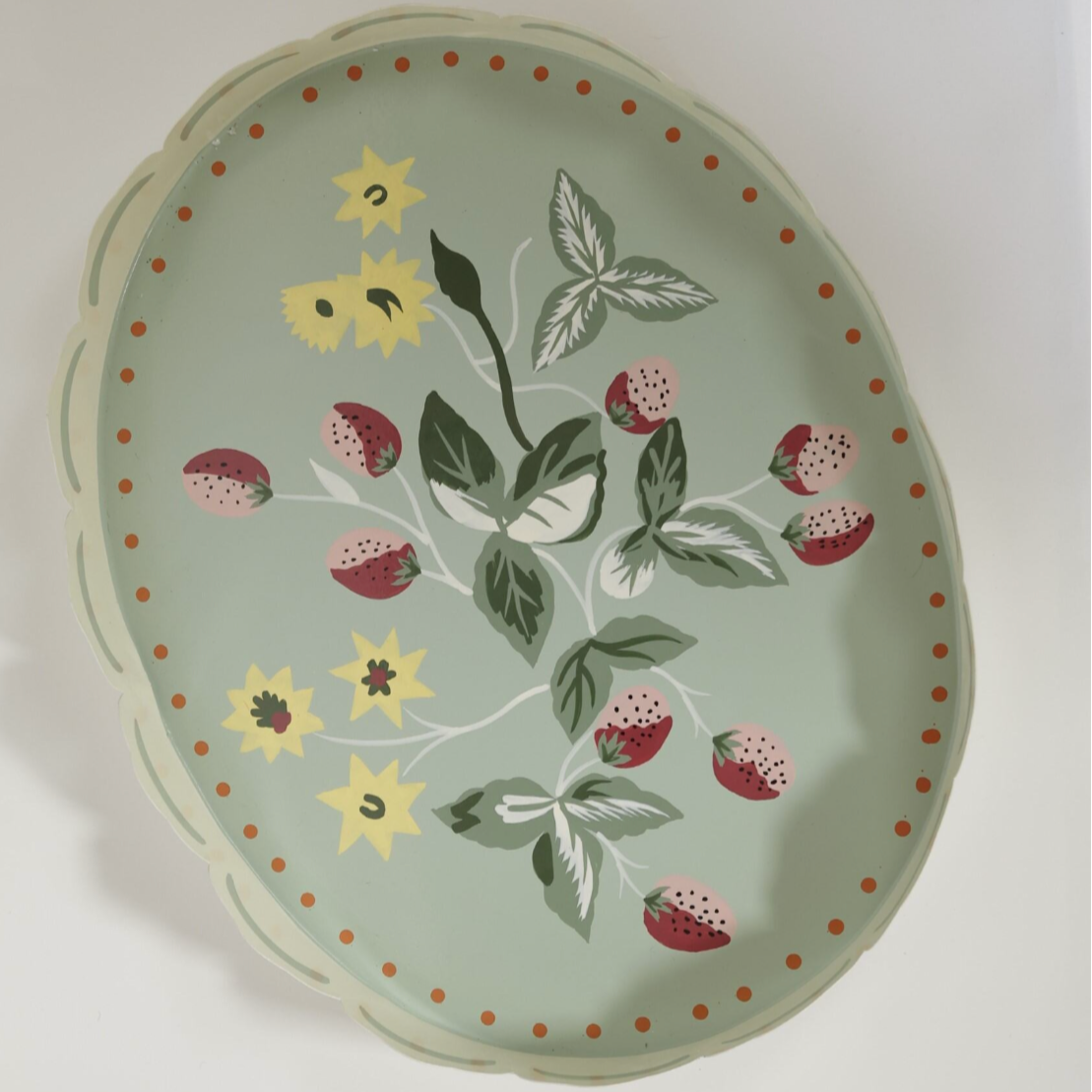 a light green strawberry tray with the base painted with strawberry and yellow flower motifs.